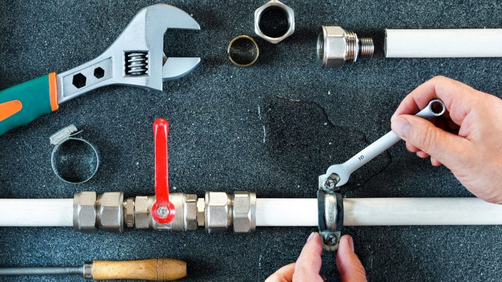 Plumber repairing a pipe valve with an adjustable wrench in Broomfield