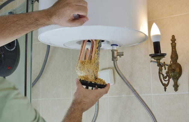 Technician removing mineral buildup from a water heater in Broomfield