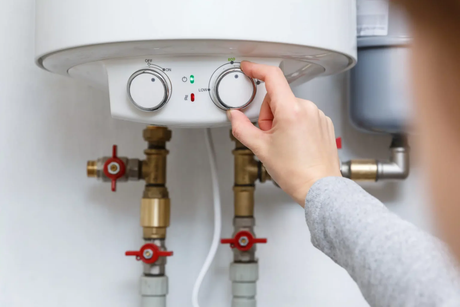 Homeowner adjusting the temperature controls on a water heater in Broomfield
